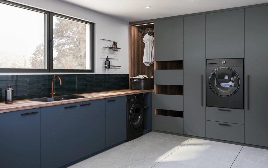 Buanderie moderne et élégante avec mobilier sur mesure gris mat, deux machines superposées (lave-linge et sèche-linge), grand plan de travail en bois clair, évier design avec robinetterie cuivre, crédence sombre, rangements spacieux, penderie ouverte avec étagères, et large fenêtre assurant lumière naturelle et vue sur l’extérieur.