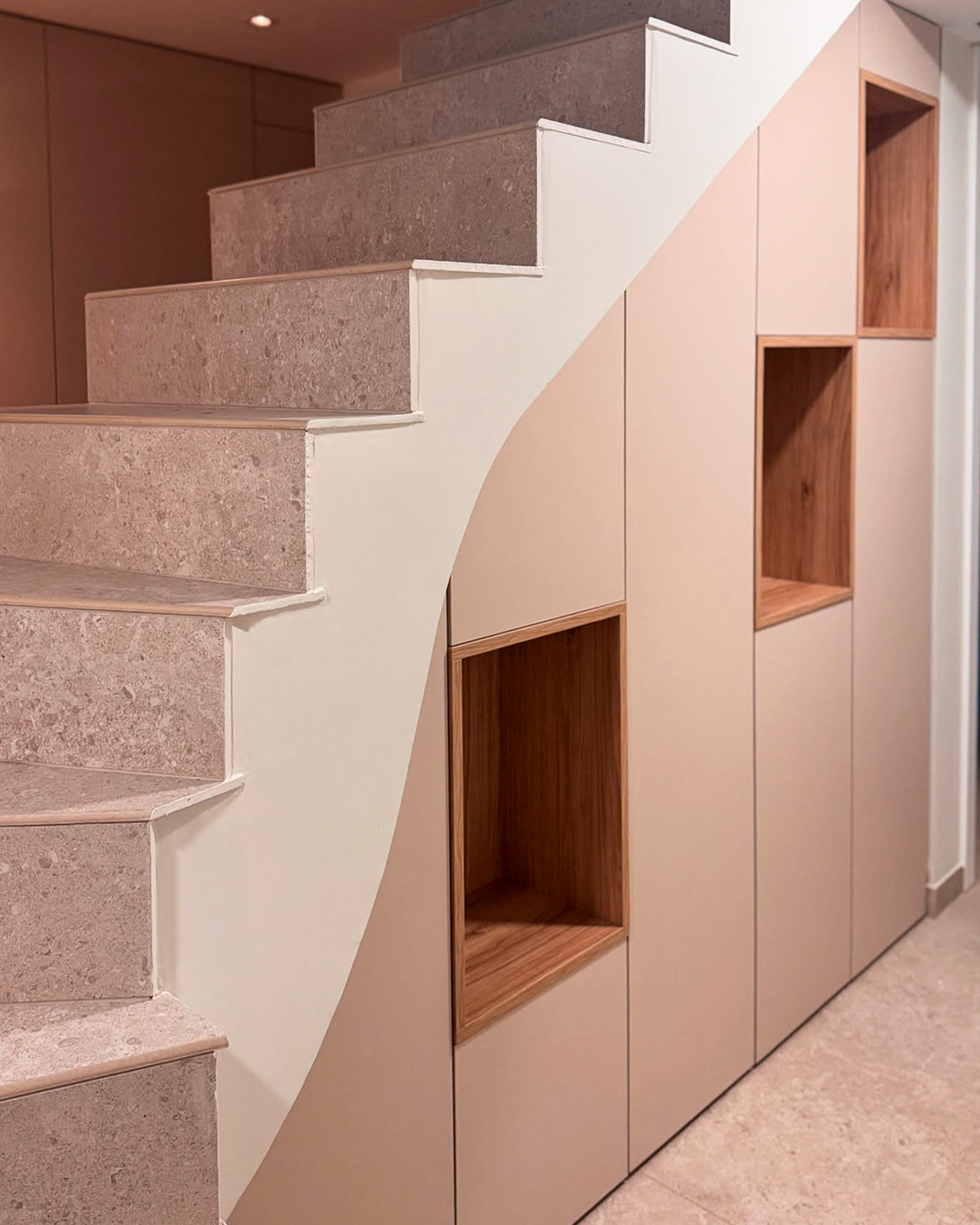 Transformez votre espace sous l’escalier en un meuble design aux finitions bois élégantes. Les niches en bois naturel créent un contraste moderne avec les portes épurées, offrant à la fois rangement discret et zones d’exposition raffinées pour la décoration intérieure.