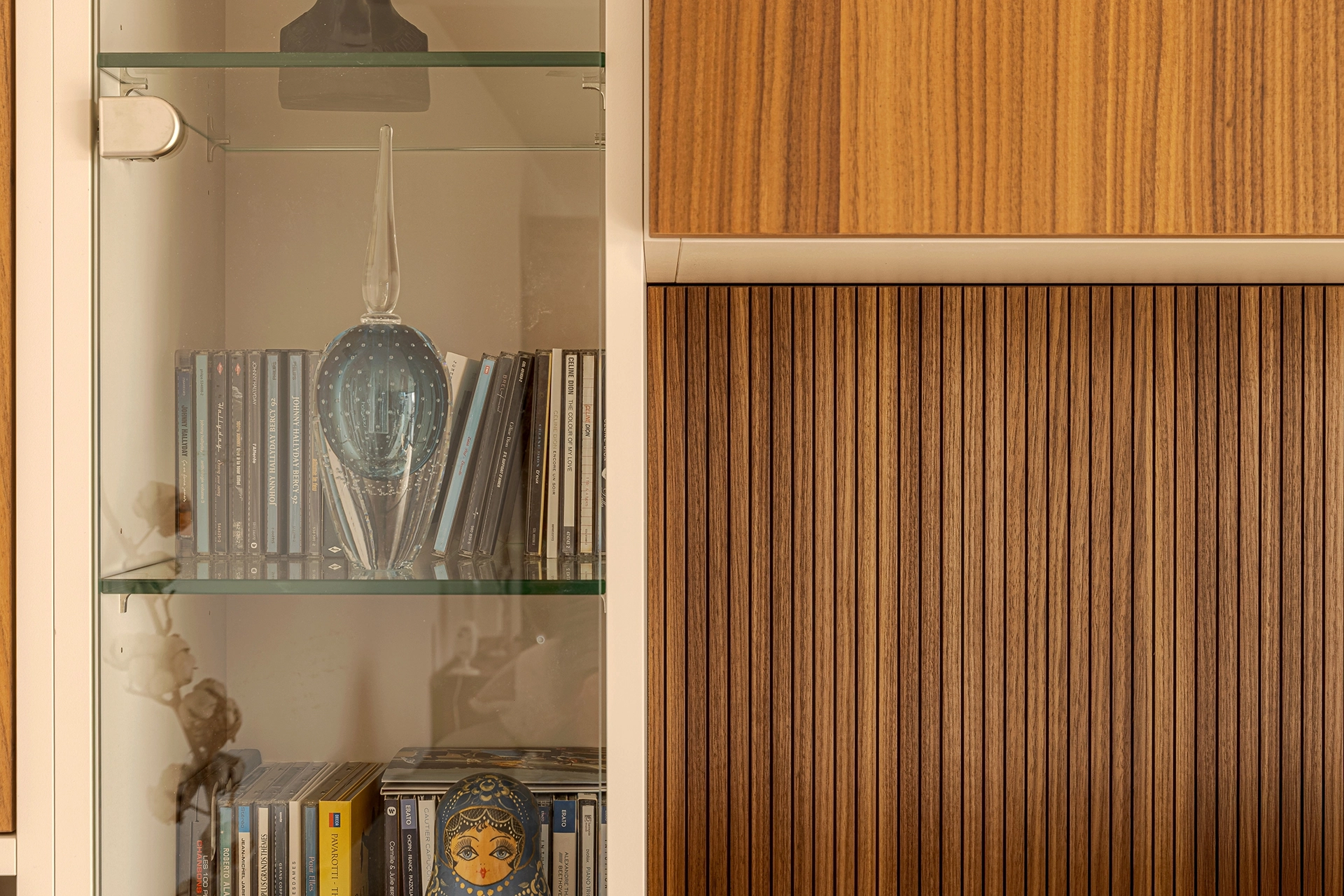 Zoom sur l’association du panneau mural bois rainuré et de la niche vitrée latérale, mettant en valeur les textures et l’assemblage soigné du meuble TV sur mesure. Intérieurs Privés Vannes