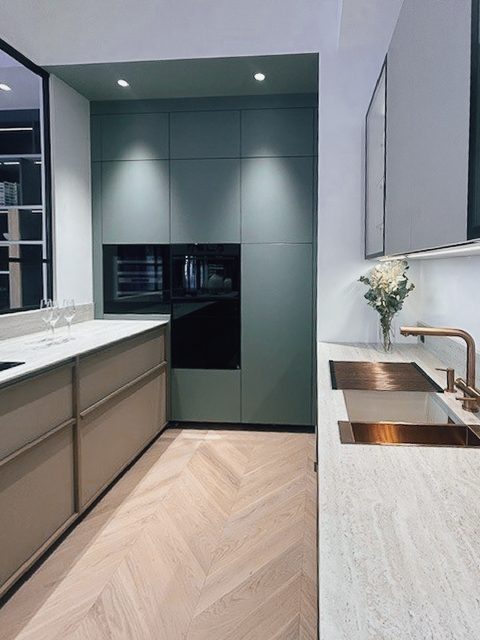 Cuisine sur mesure aux façades vert mat avec électroménager intégré et lignes épurées, exposée au showroom Intérieurs Privés Paris 6. Un aménagement pensé pour la continuité visuelle et la qualité des finitions.