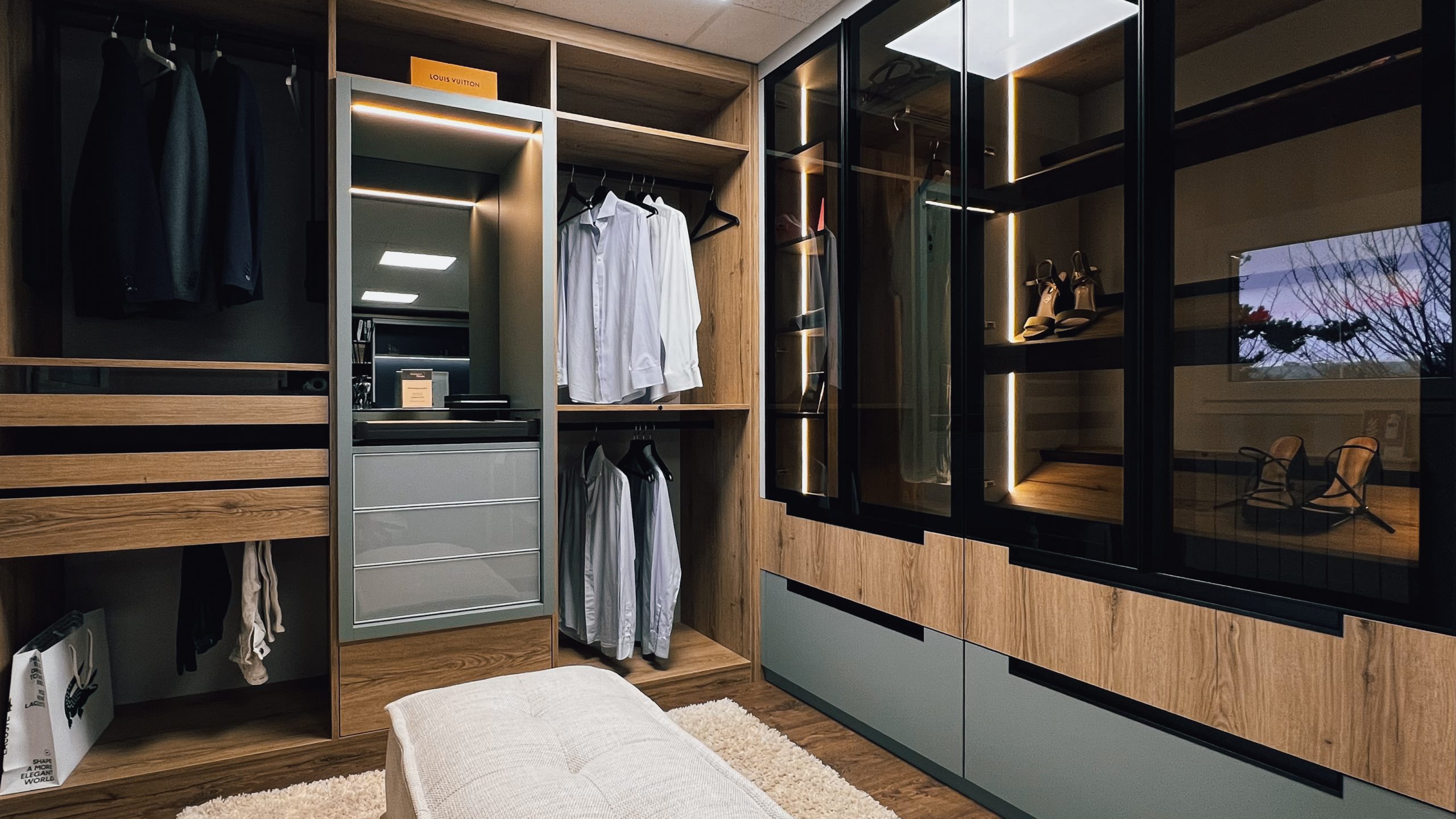 Dressing sur mesure présenté au showroom Intérieurs Privés de Saint-Germain-en-Laye, mêlant bois, façades vitrées et éclairage intégré. Une conception pensée pour organiser les volumes et mettre en valeur les finitions.