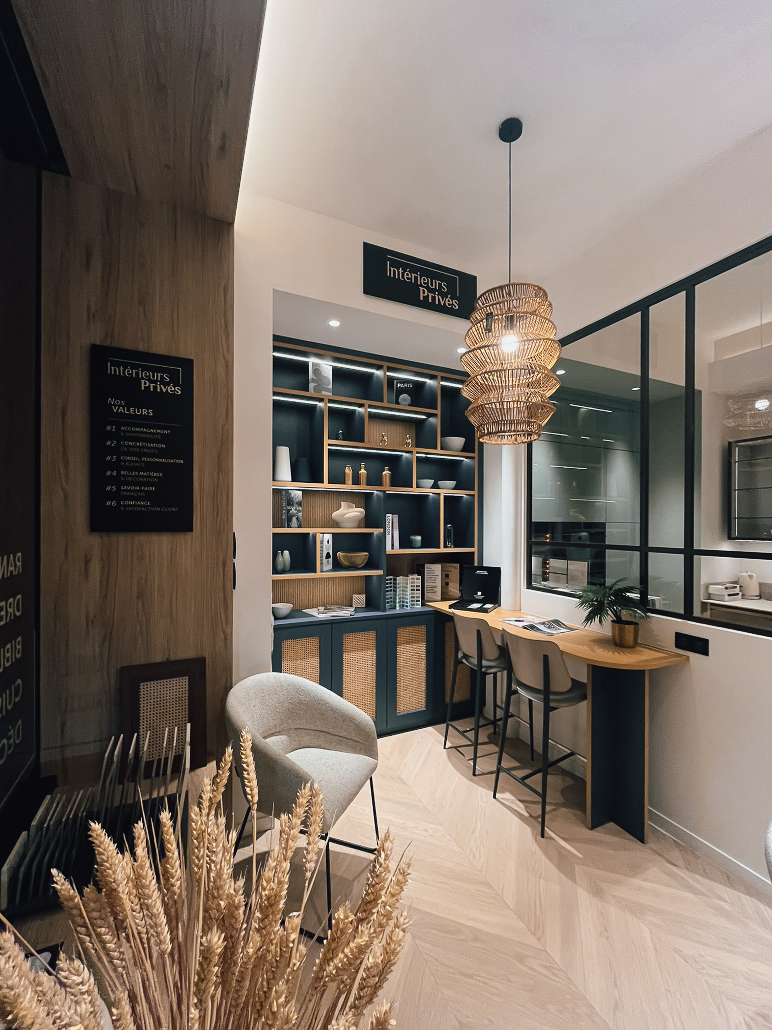 Espace conseil du showroom Intérieurs Privés Paris 6 avec bibliothèque sur mesure, étagères rétro-éclairées, rangements fermés et coin bar intégré. Une mise en scène élégante du savoir-faire en aménagement intérieur sur mesure.