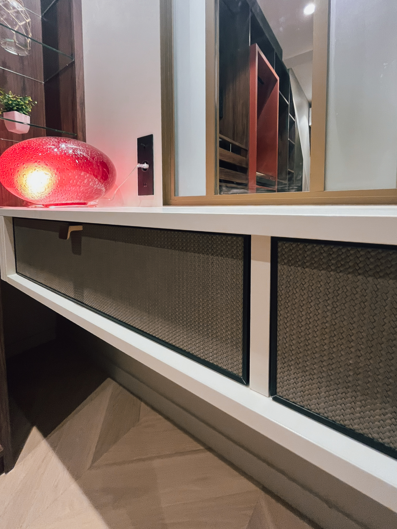 Détail de rangement bas sur mesure exposé au showroom Intérieurs Privés Paris 6, avec façades texturées, prises de main intégrées et finitions soignées. Une approche précise du mobilier sur mesure et du travail des matières.