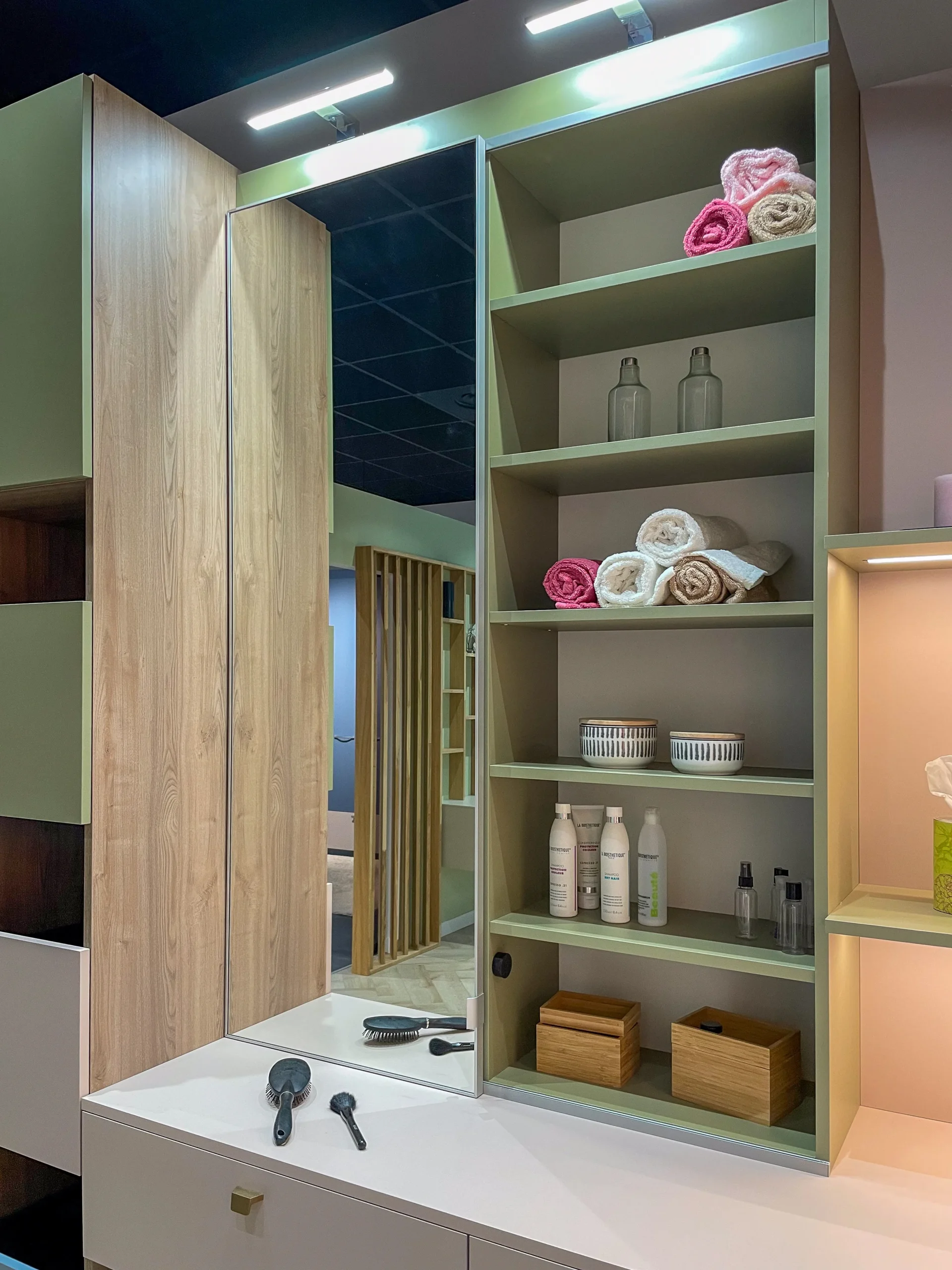 Armoire miroir avec étagères ouvertes, rangements pour serviettes et meuble bas suspendu dans une salle de bain sur-mesure.