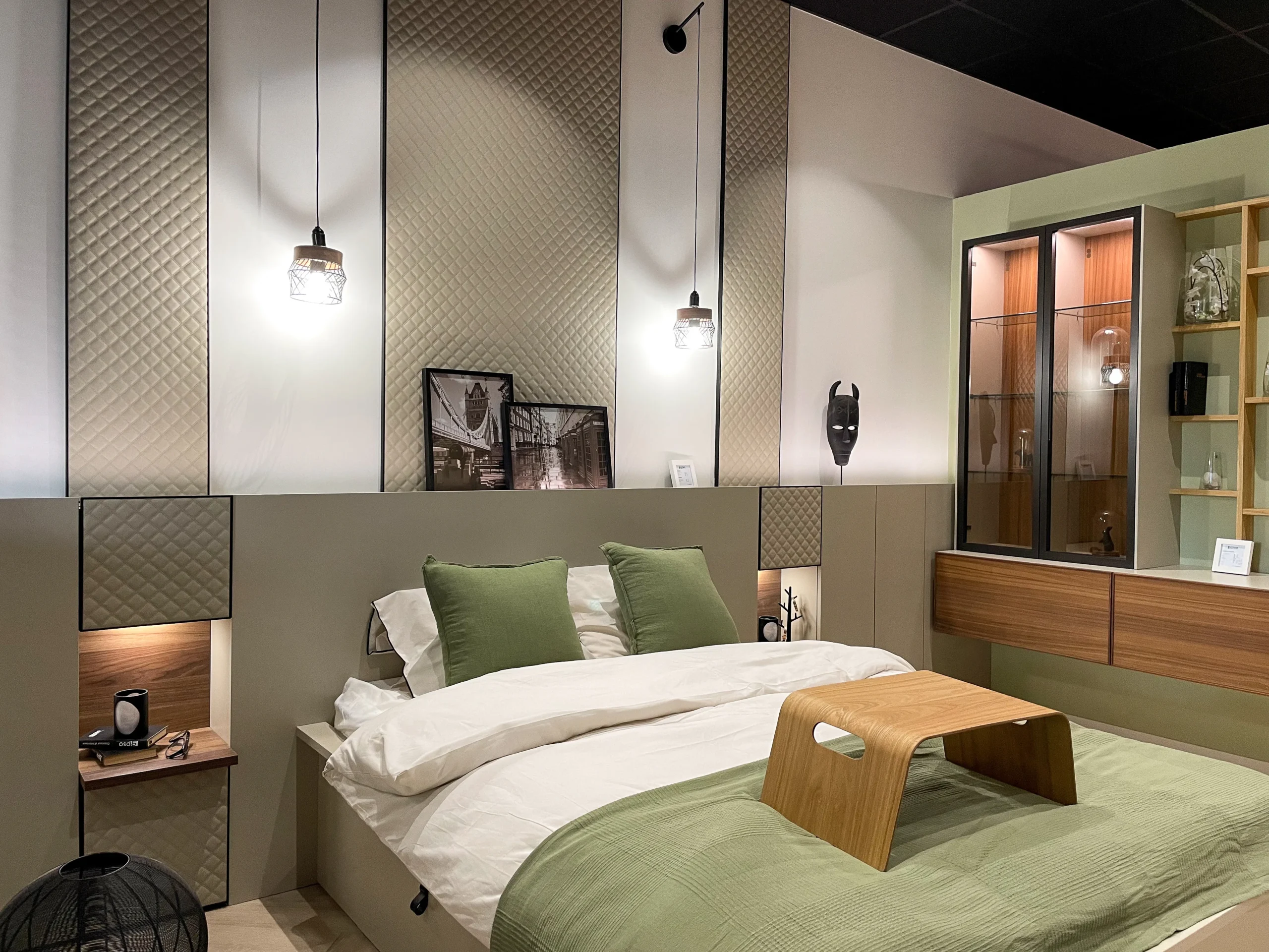 Chambre avec tête de lit sur-mesure, panneaux décoratifs, niches éclairées et linge de lit vert sauge.