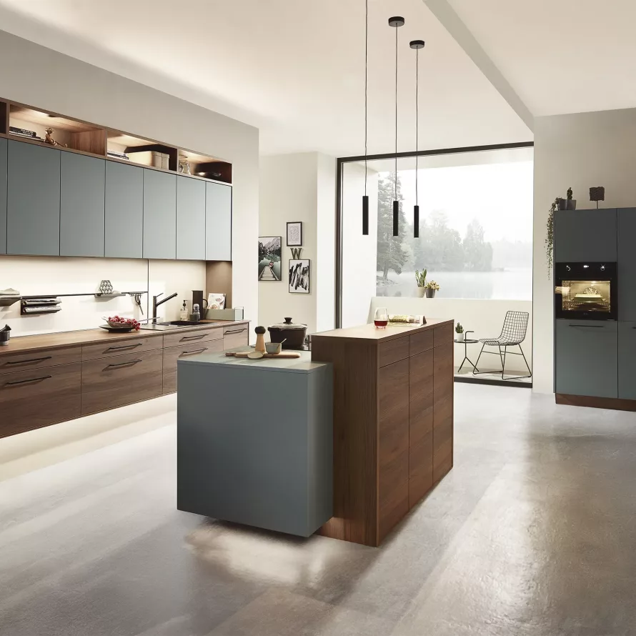 Cuisine sur-mesure contemporaine associant façades bois et gris, grand linéaire de rangement, îlot central et colonnes électroménager intégrées.