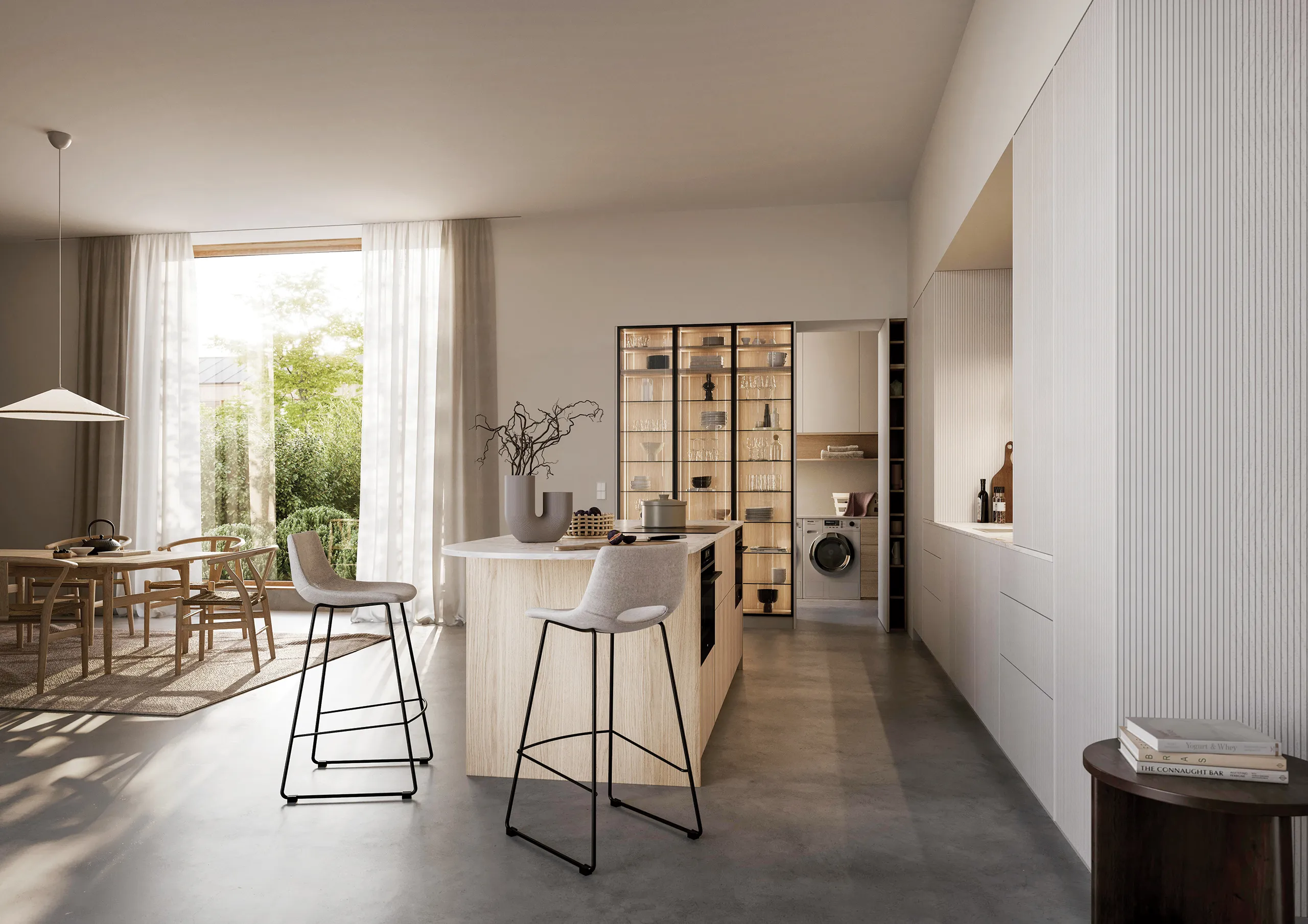 Cuisine sur-mesure lumineuse avec îlot central en bois clair, espace repas, rangements intégrés et buanderie discrète en arrière-plan.