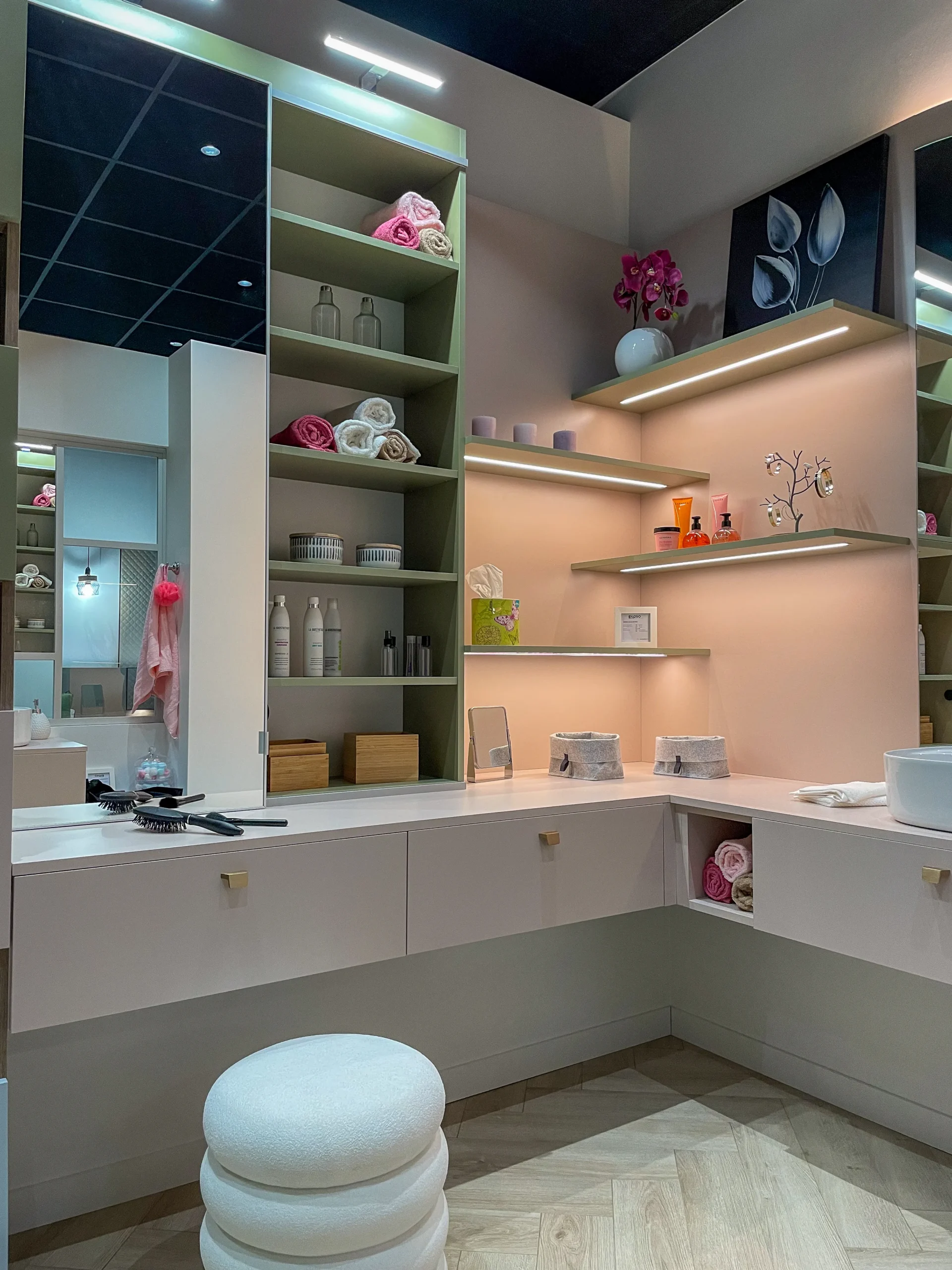 Étagères murales de salle de bain avec éclairage intégré, niches vert sauge et plan de toilette sur-mesure.