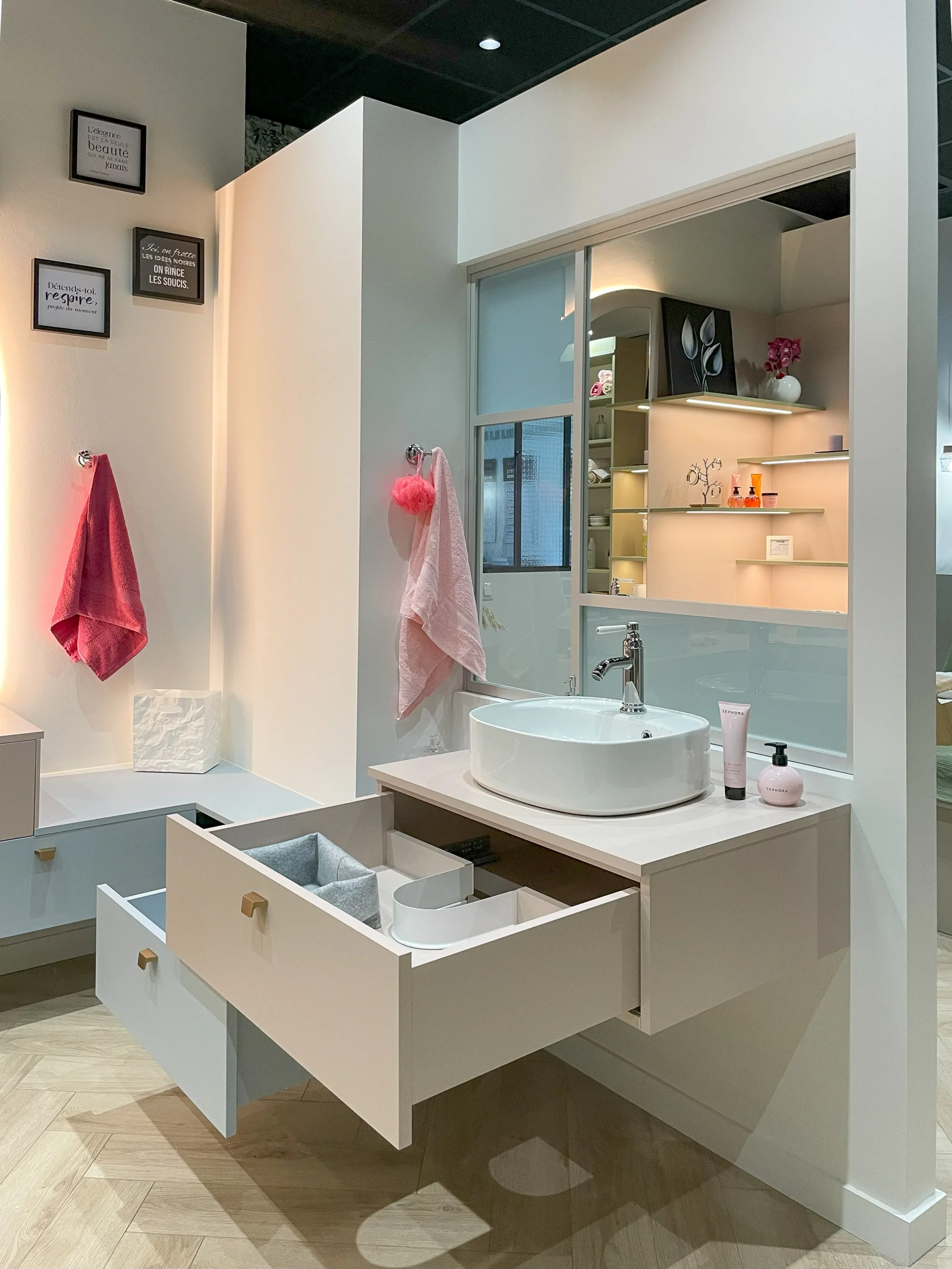 Meuble de salle de bain suspendu avec vasque posée, tiroirs ouverts et rangements intégrés.