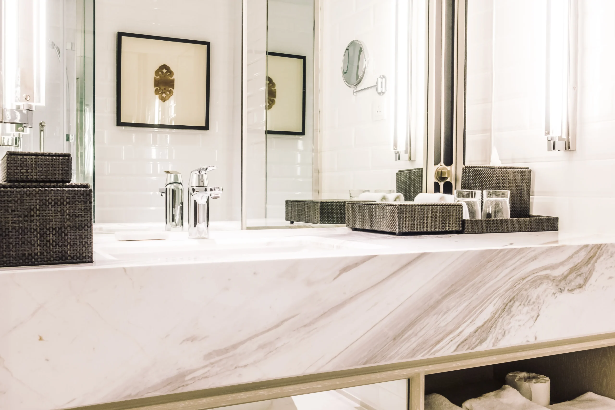 Salle de bain lumineuse avec plan vasque effet marbre, miroirs intégrés, robinet chromé et rangements décoratifs.