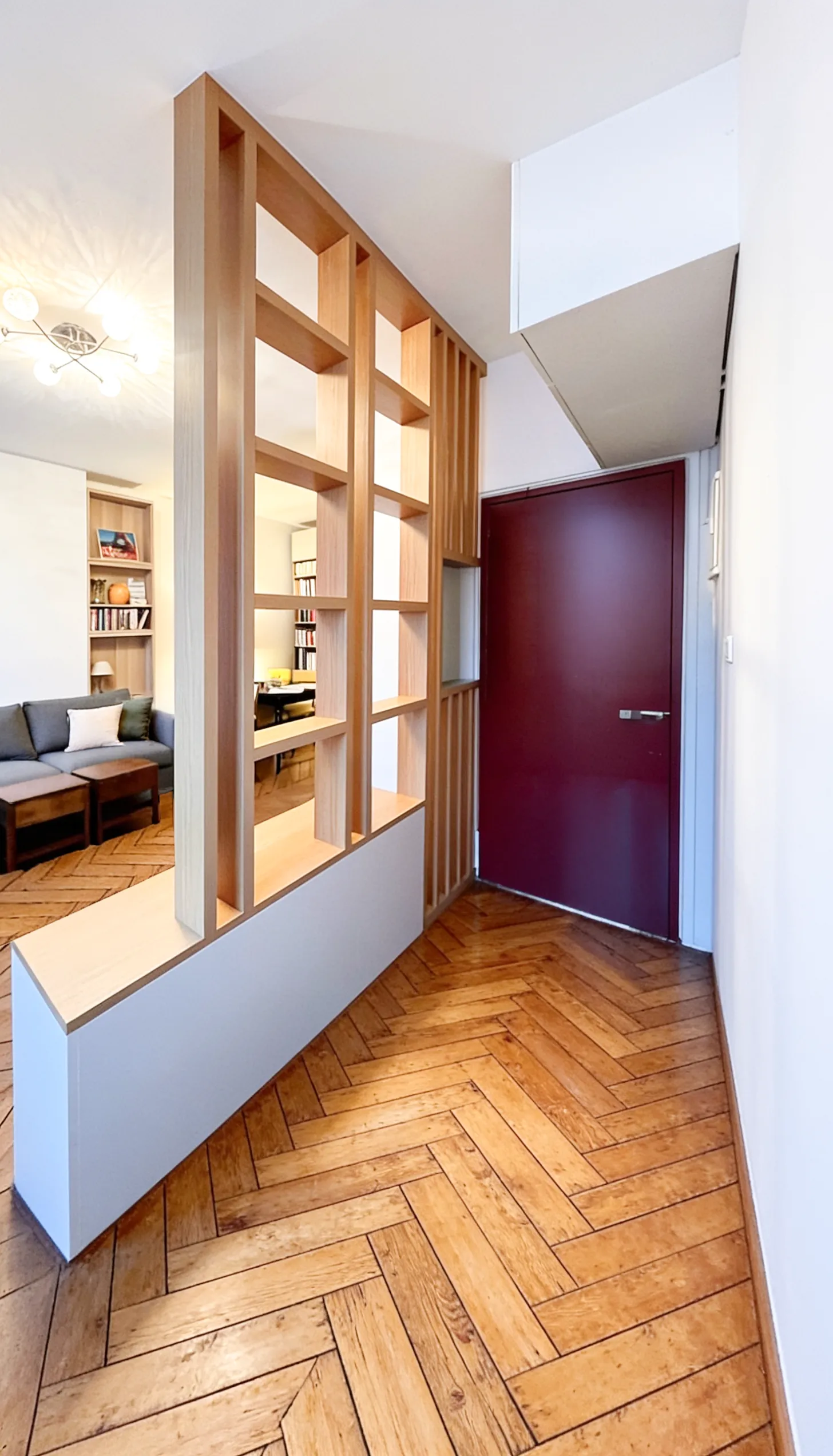 Aménagement sur-mesure en bois associant claustra, étagères ouvertes et meuble TV pour structurer le salon.