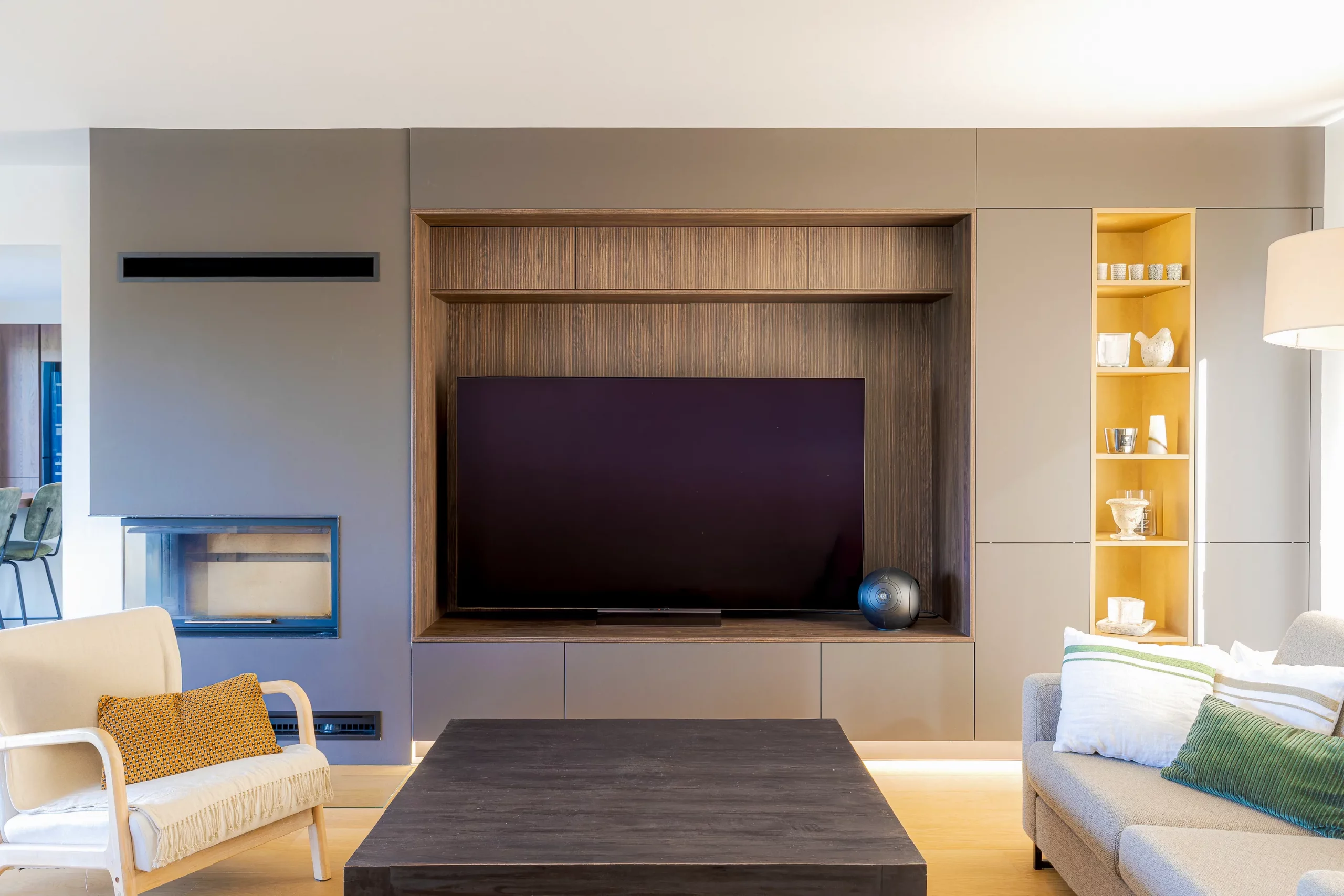 Meuble TV mural sur mesure avec encadrement bois, façades taupe, cheminée latérale et étagère décorative rétroéclairée.