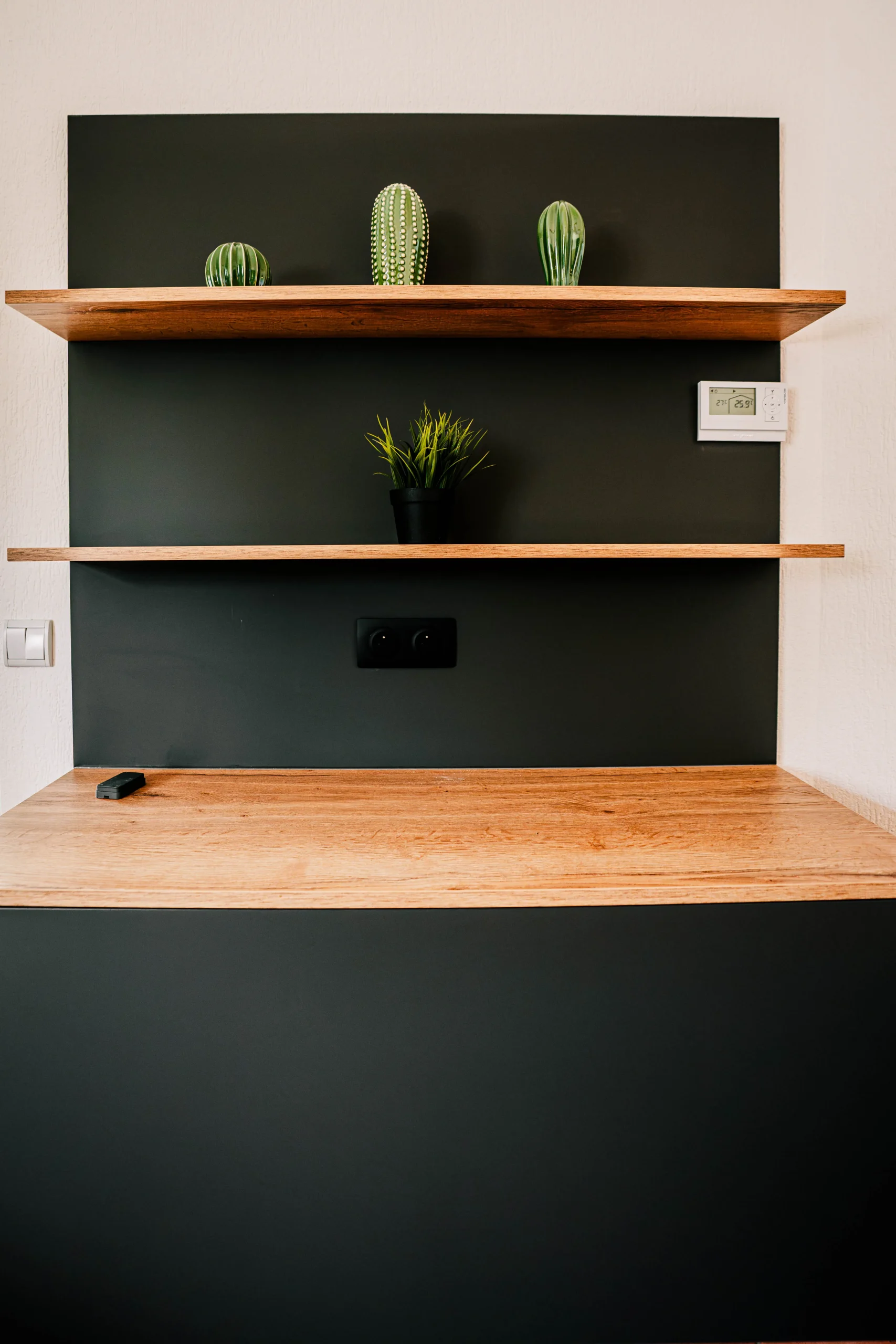 Aménagement complémentaire avec meuble noir, étagères en bois et plan de travail assorti à la cuisine sur-mesure de Kembs.