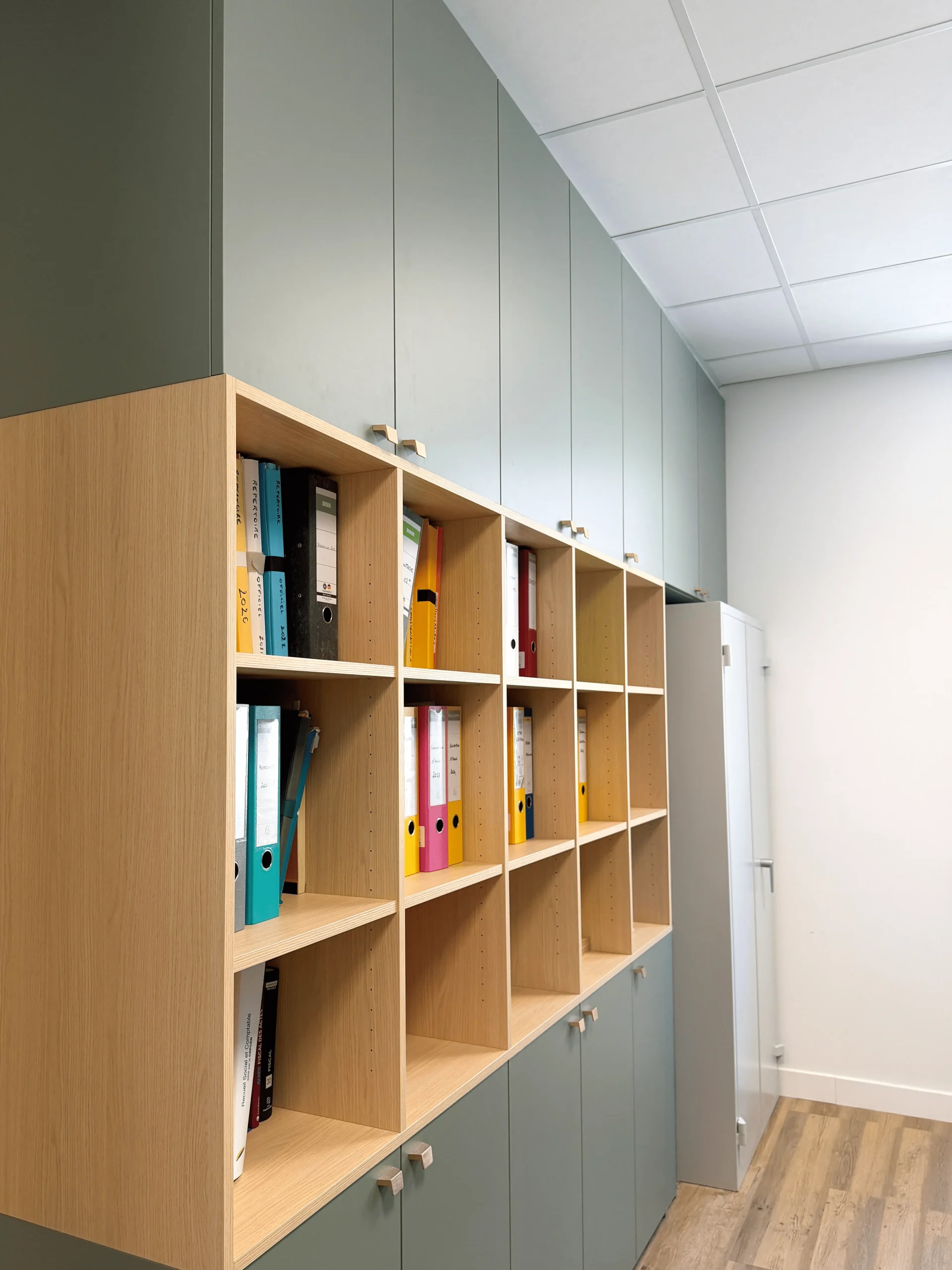 Rangements sur-mesure pour bureau professionnel à Lannion, avec niches ouvertes, classeurs, façades vertes et structure en bois clair.
