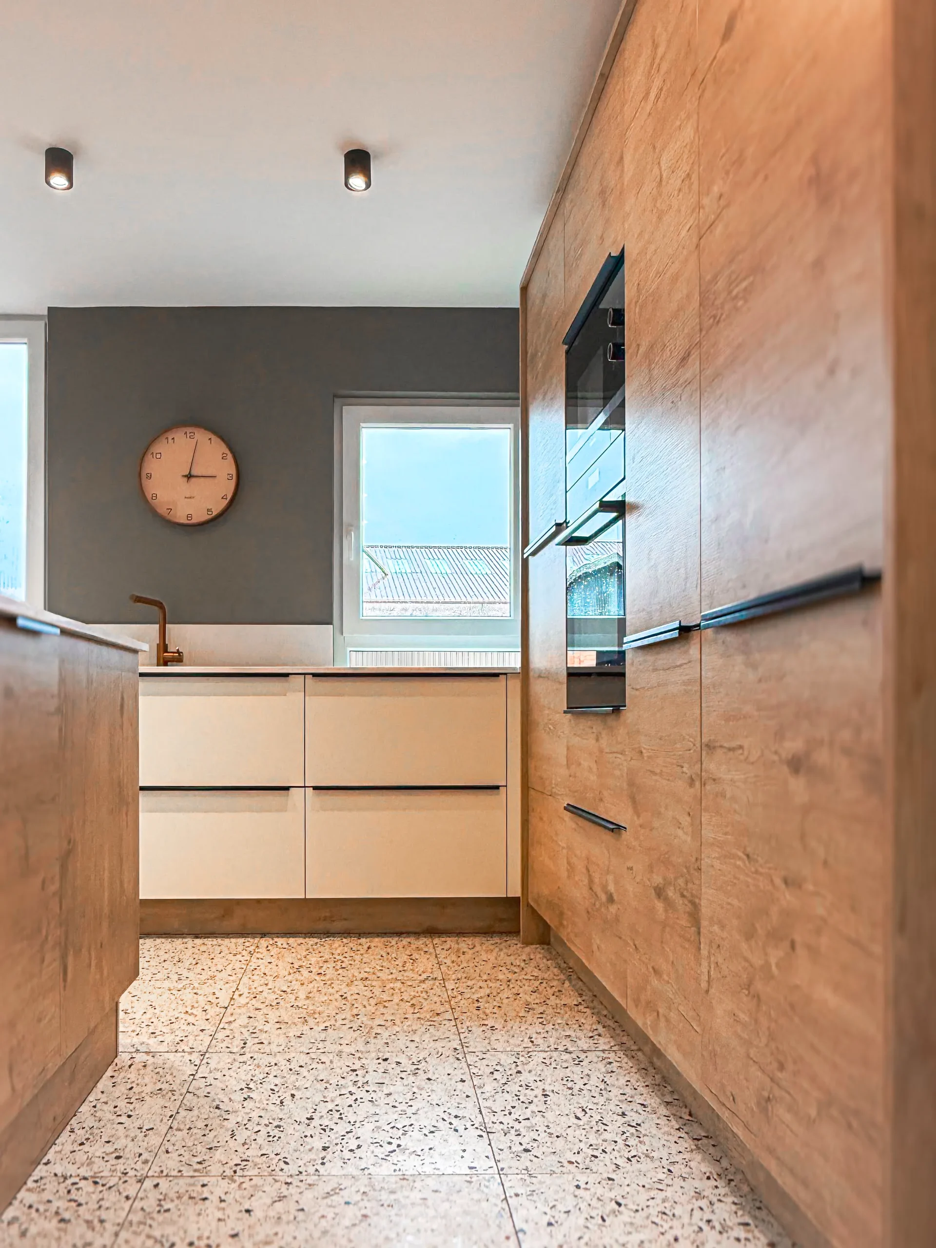 Ensemble de colonnes toute hauteur en décor bois avec électroménager encastré et rangements intégrés.