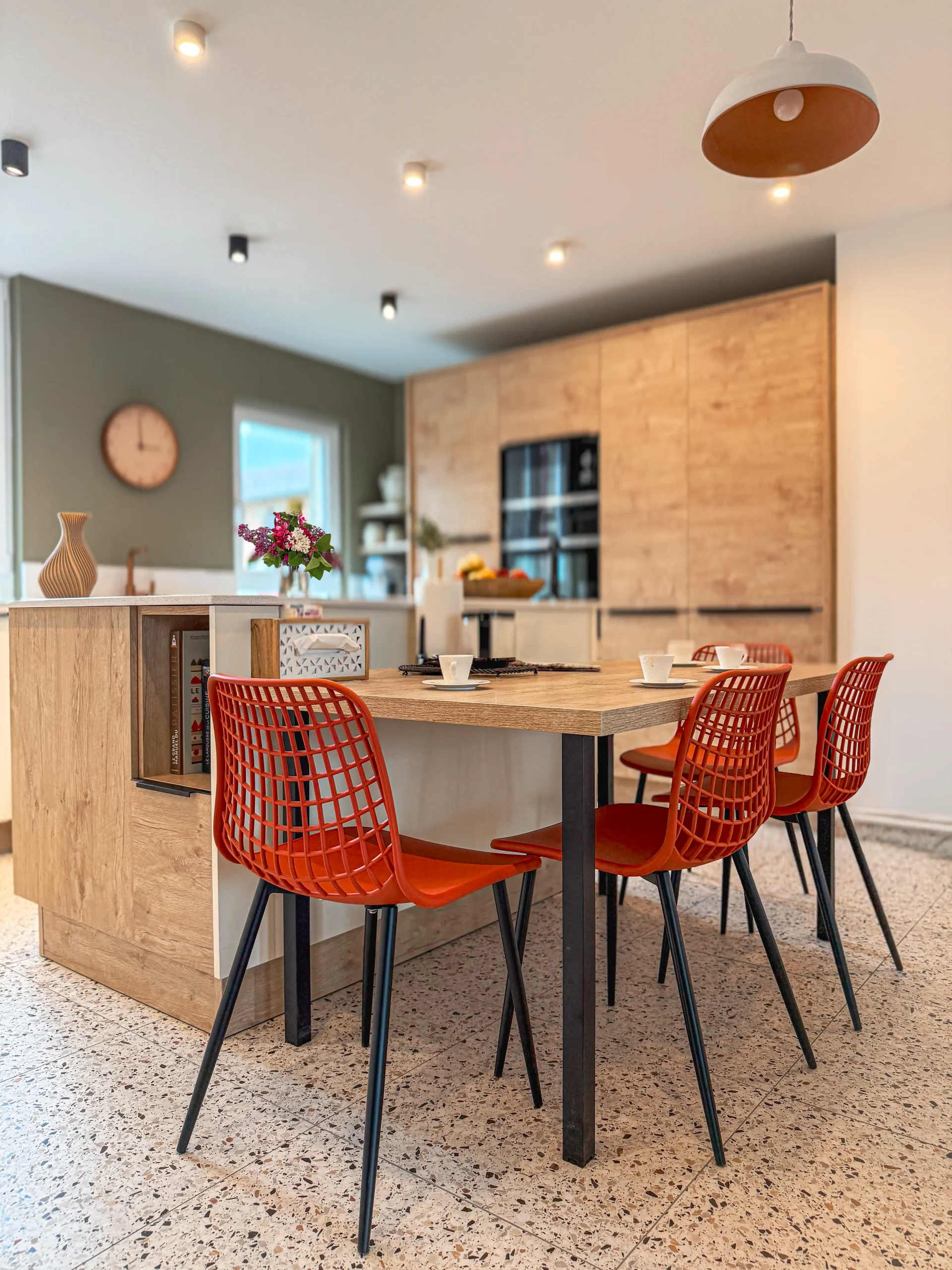 Cuisine sur-mesure avec table repas intégrée à l’aménagement, décor bois et assises colorées à Bar-le-Duc.