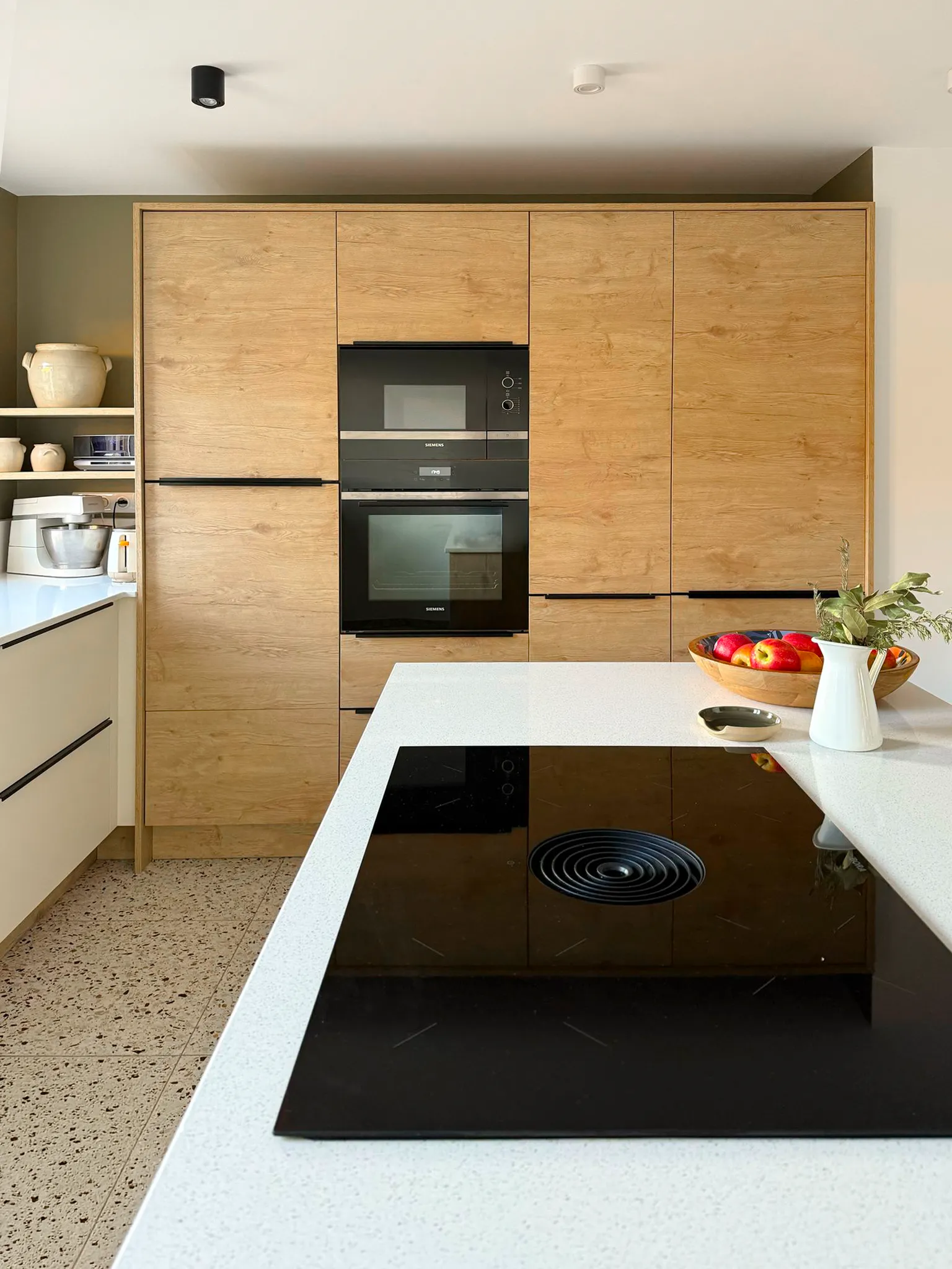 Cuisine sur-mesure à Bar-le-Duc avec colonnes en décor bois, électroménager intégré et îlot avec plaque de cuisson.