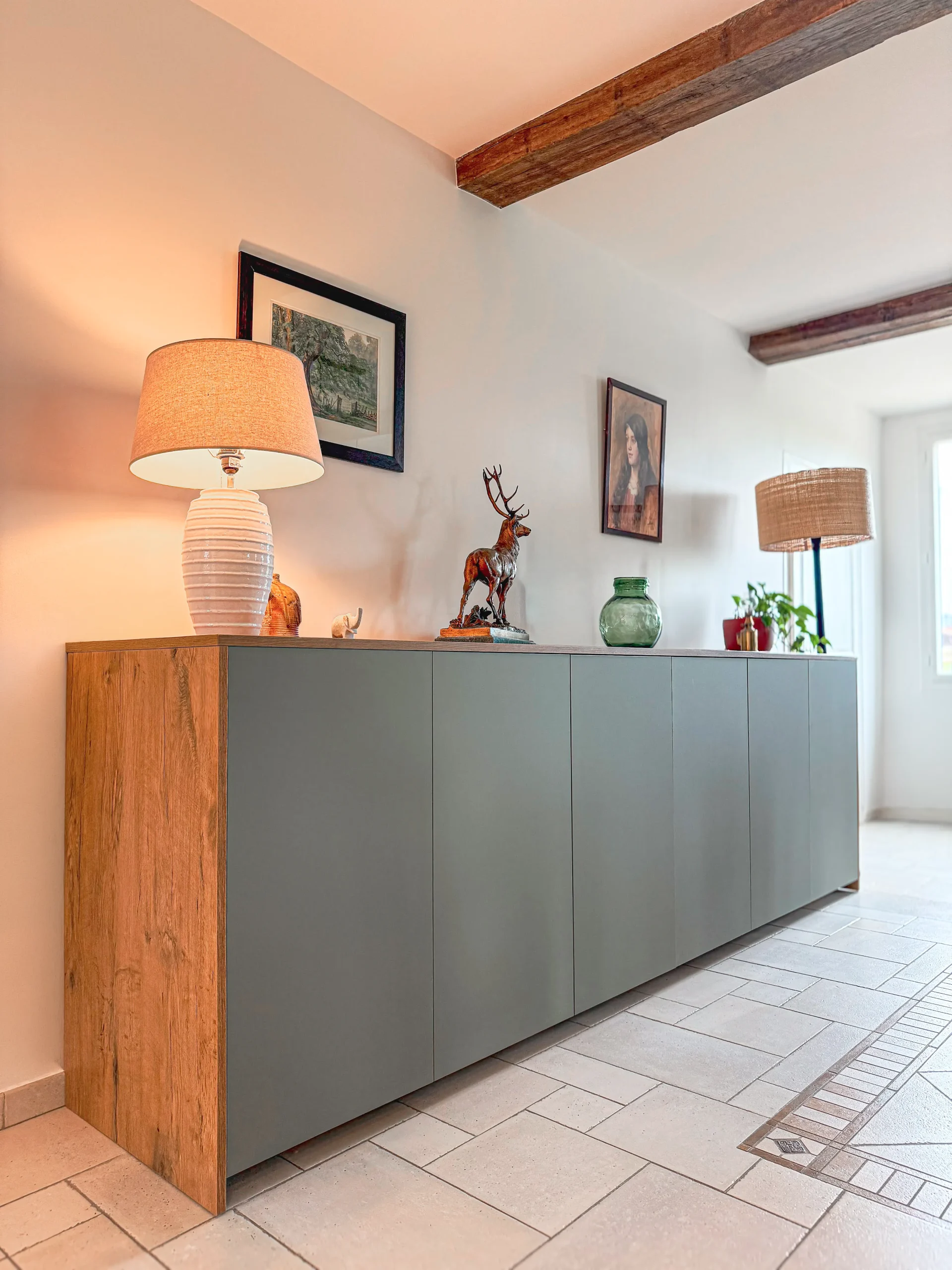 Meuble bas sur-mesure associant façades vert gris et habillage bois dans la pièce de vie.
